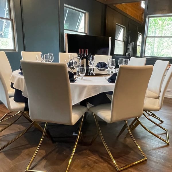 Round dining table set with white tablecloth, wine bottles, glasses, and modern chairs at Eastern Pavilion.